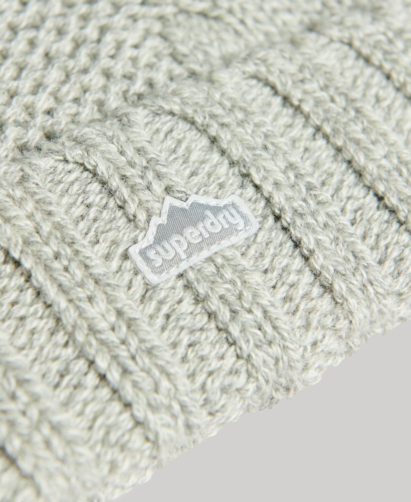 gorro de malha trançada com pompons em tweed cinza claro.