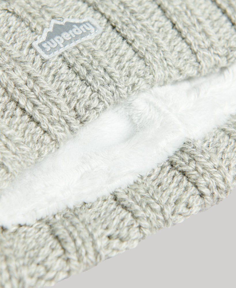 gorro de malha trançada com pompons em tweed cinza claro.