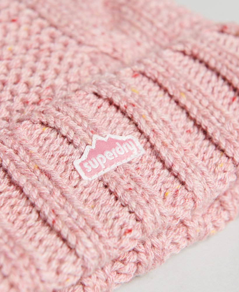 gorro de malha trançada com pompom em tweed rosa.