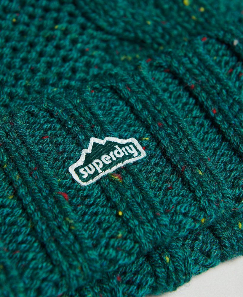 gorro de malha trançada com pompom em tweed verde-floresta.