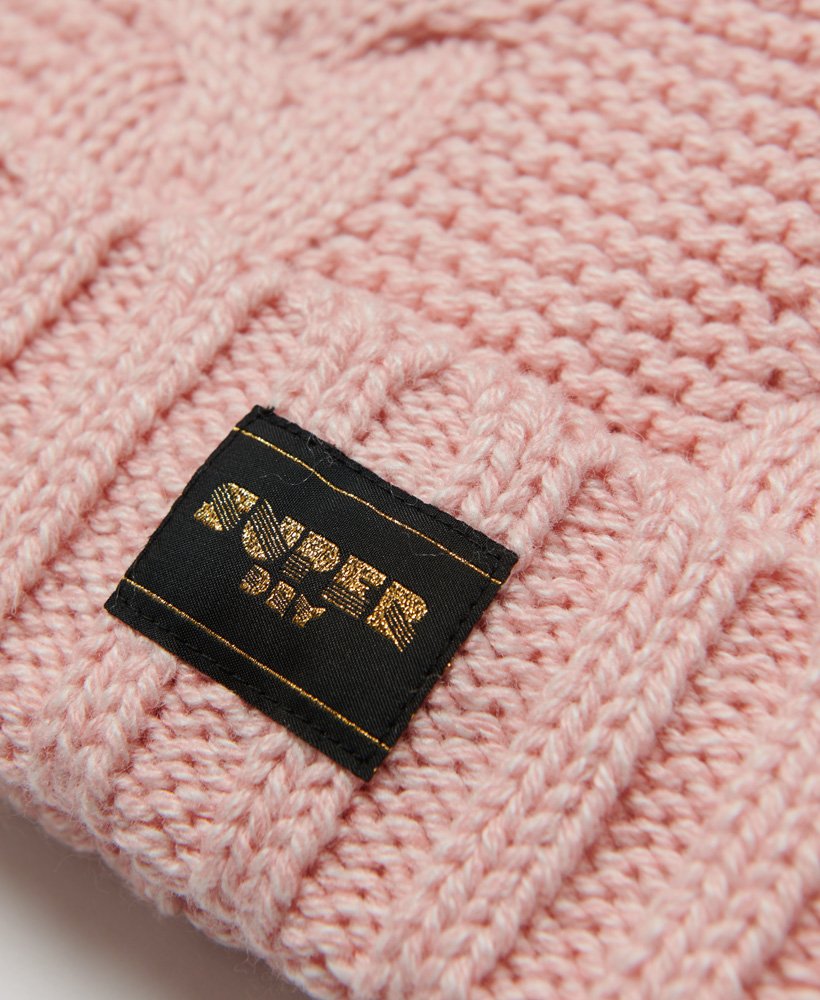 gorro de malha trançada com detalhes em rosa.