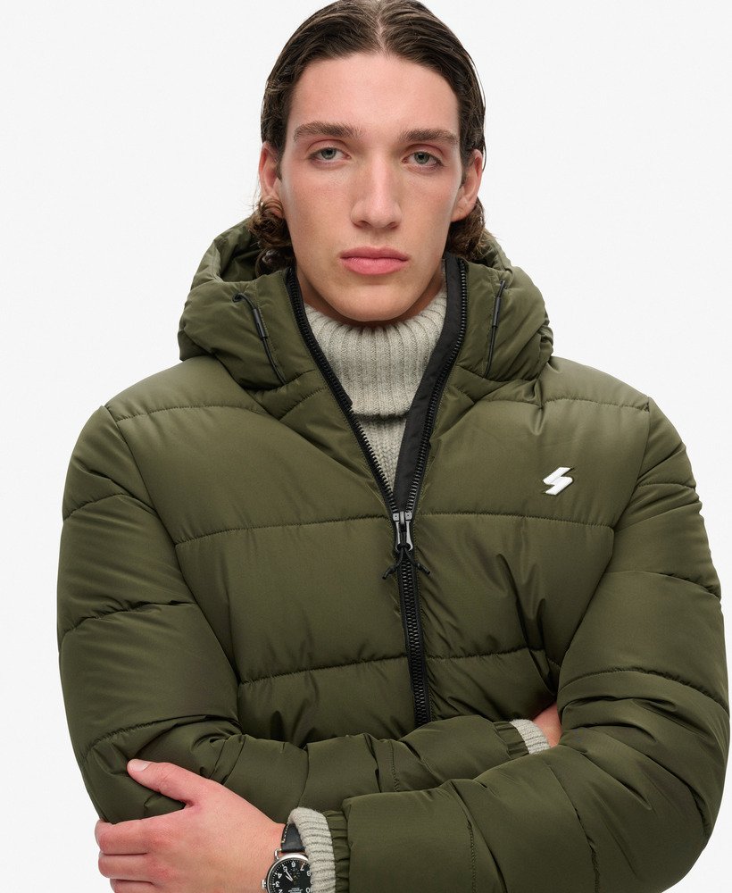 jaqueta esportiva puffer com capuz na cor verde musgo escuro.