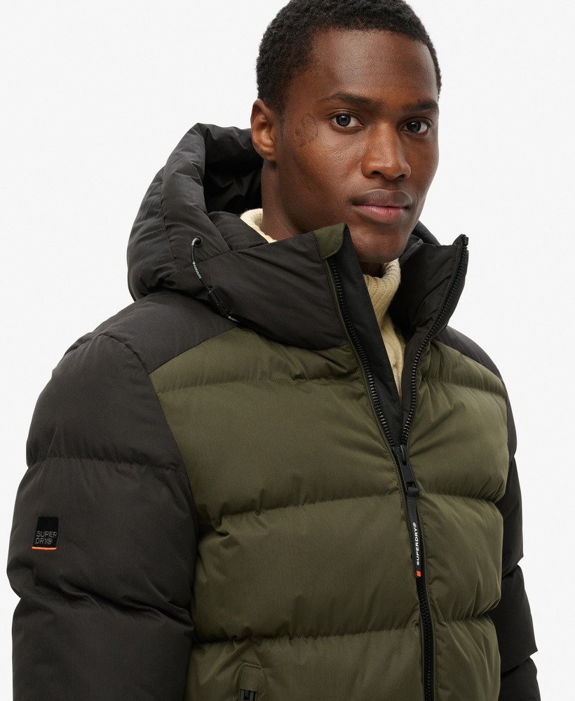 jaqueta puffer esportiva com capuz e blocos de cores na cor preta.