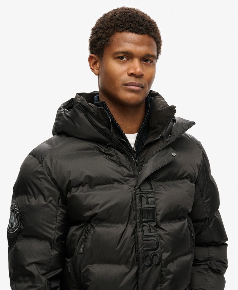 jaqueta puffer com capuz e estampa da cidade na cor preta.