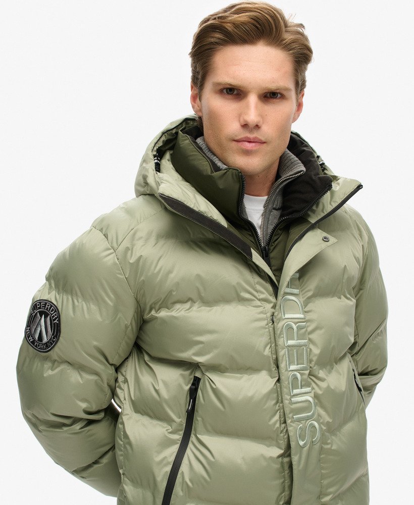 jaqueta puffer com capuz e estampa da cidade na cor verde-marinho.
