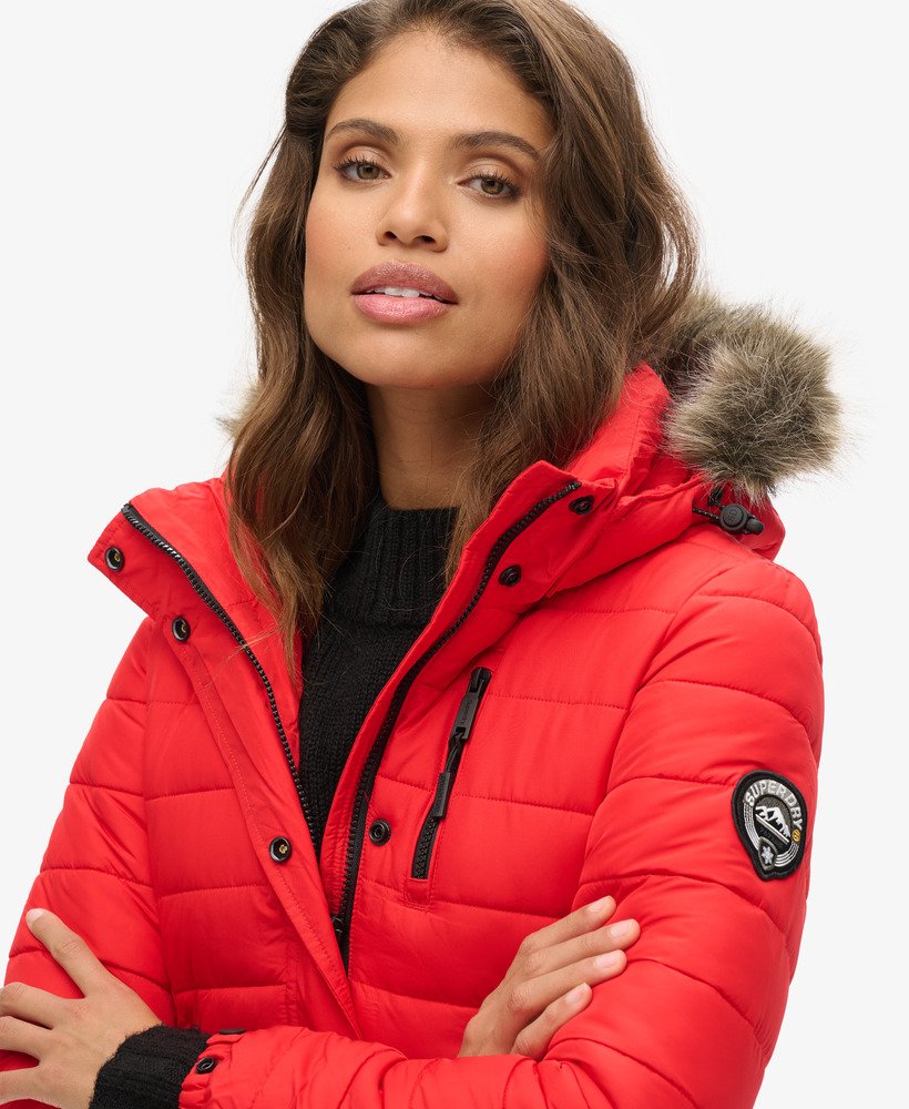 jaqueta puffer de comprimento médio com capuz e forro de pele sintética na cor vermelho high risk.