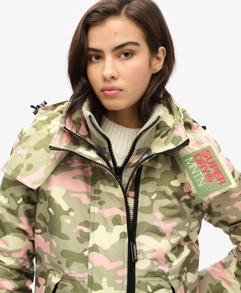 jaqueta corta-vento com capuz para montanha em camuflagem rosa e verde-marinho.
