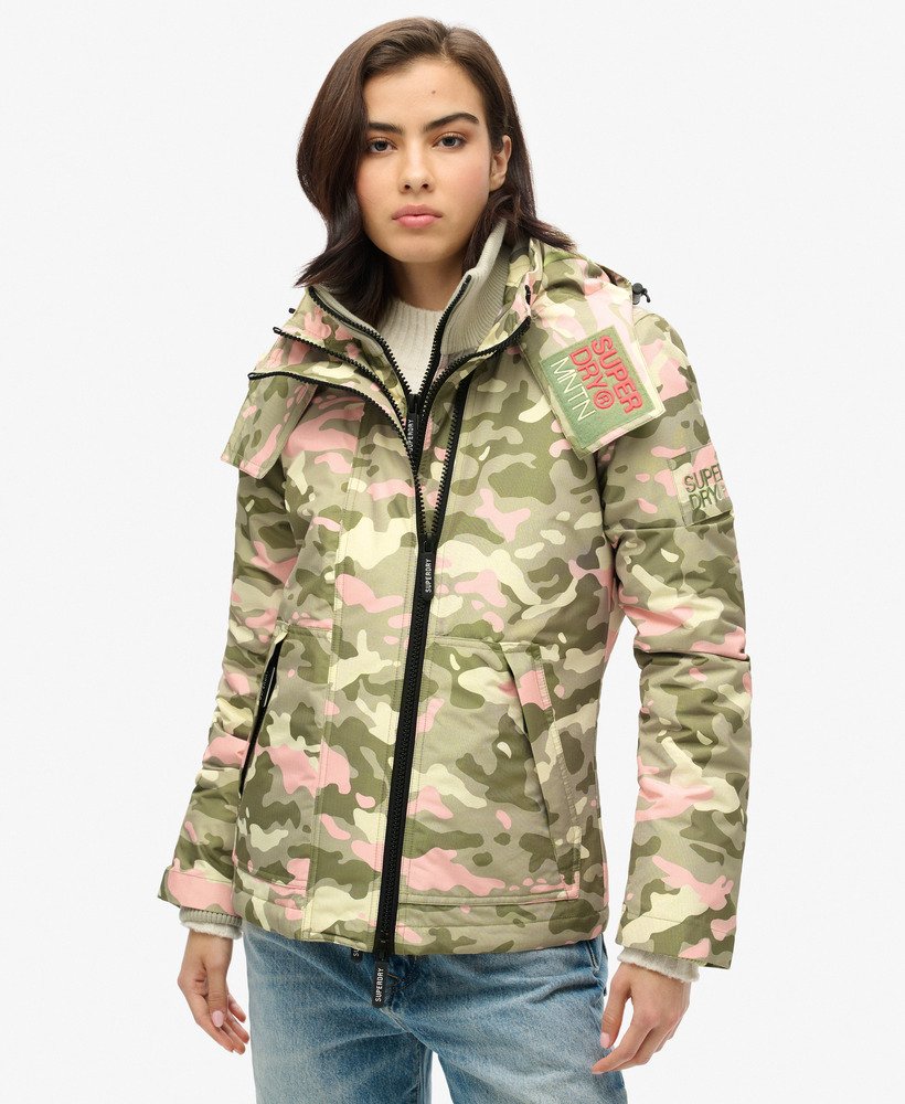 jaqueta corta-vento com capuz para montanha em camuflagem rosa e verde-marinho.