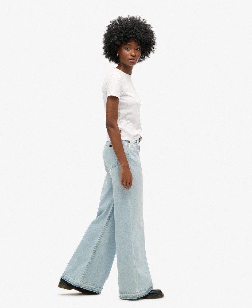 calça jeans flare de perna larga com barra desfiada na cor azul claro phoenix.