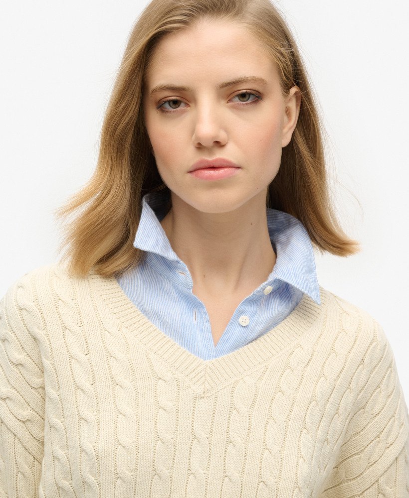 suéter oversized com decote em v e tranças na cor bege aveia.