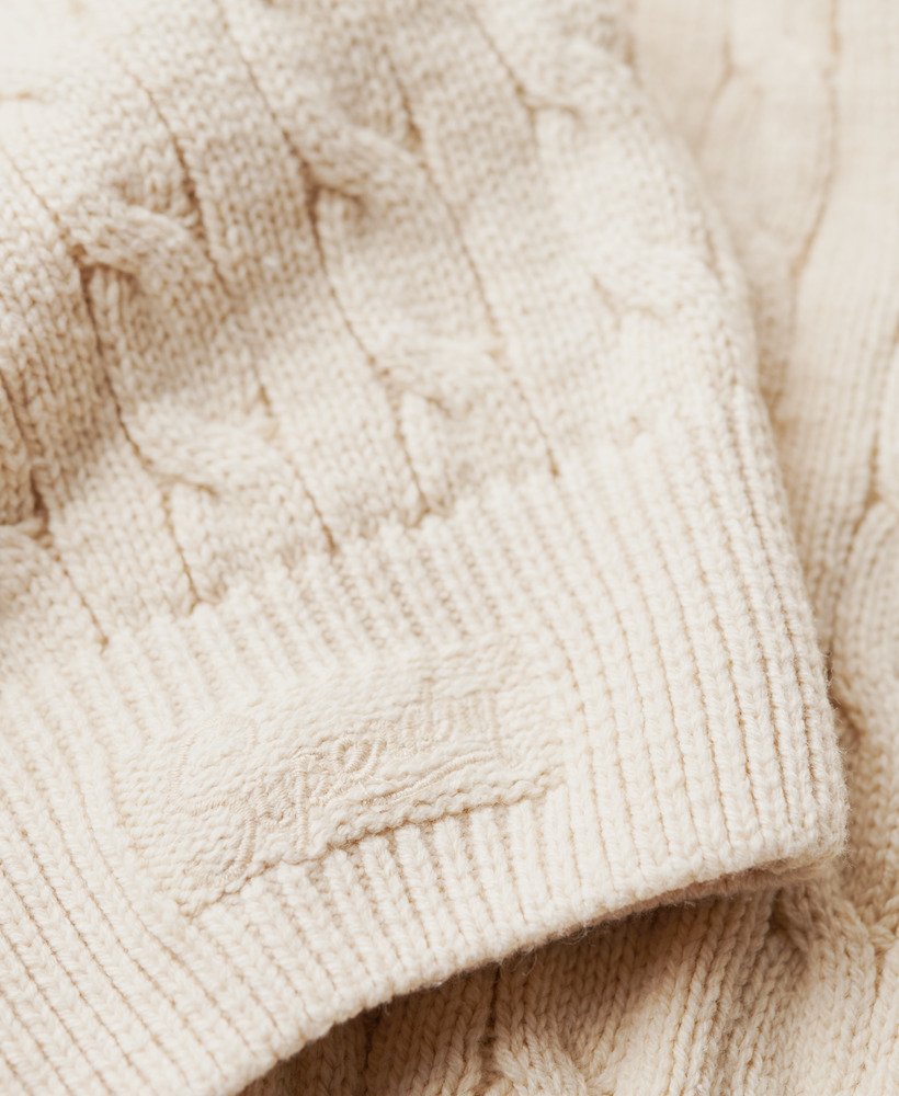 suéter oversized com decote em v e tranças na cor bege aveia.