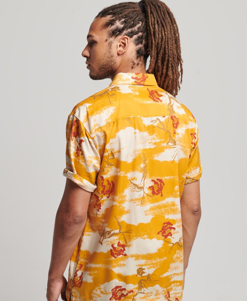 camisa havaiana de manga curta com estampa de nuvens amarelas.