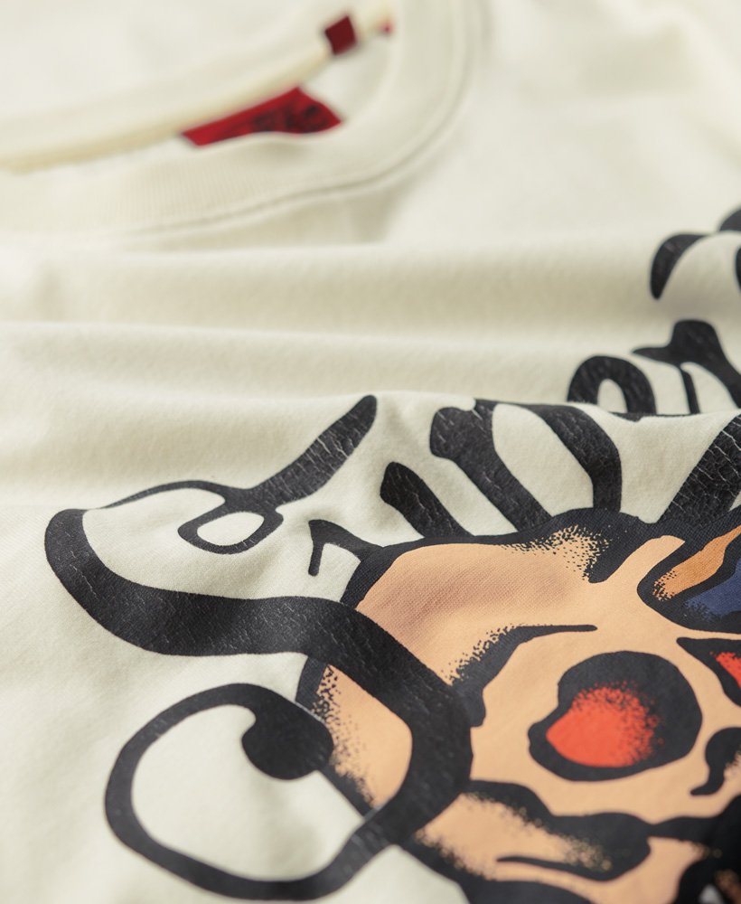 camiseta com estampa frontal de escrita cursiva estilo tatuagem na cor off white.