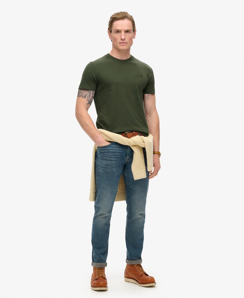 camiseta essential logo em algodão orgânico dentro de uma bolsa de viagem verde.