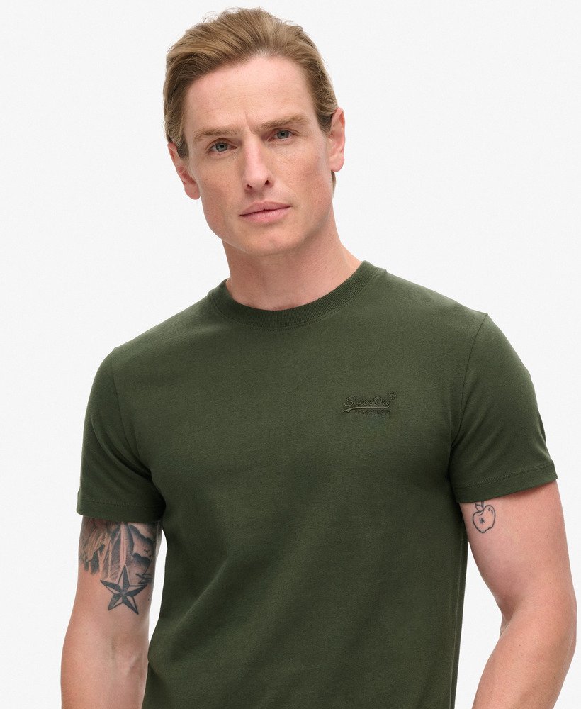 camiseta essential logo em algodão orgânico dentro de uma bolsa de viagem verde.