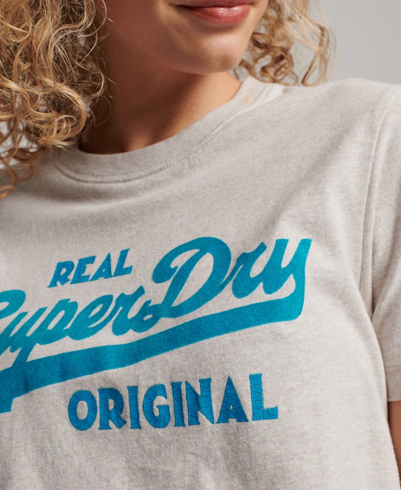 camiseta de algodão orgânico com estampa vintage do logo em cursiva na cor aveia mesclada.