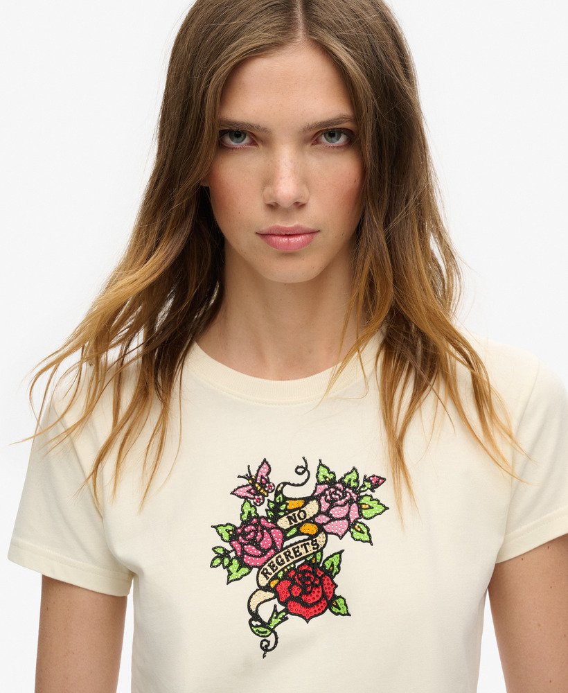 camiseta justa com estampa de tatuagem pequena e strass na cor branca arroz.