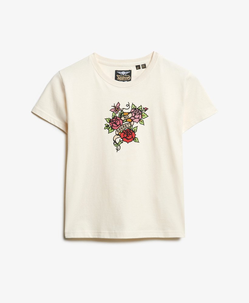 camiseta justa com estampa de tatuagem pequena e strass na cor branca arroz.