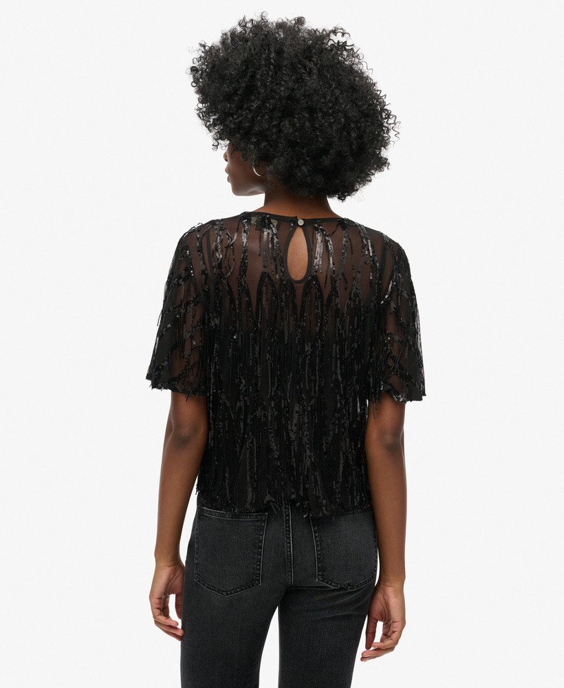 blusa transparente de manga curta com lantejoulas e franjas pretas.